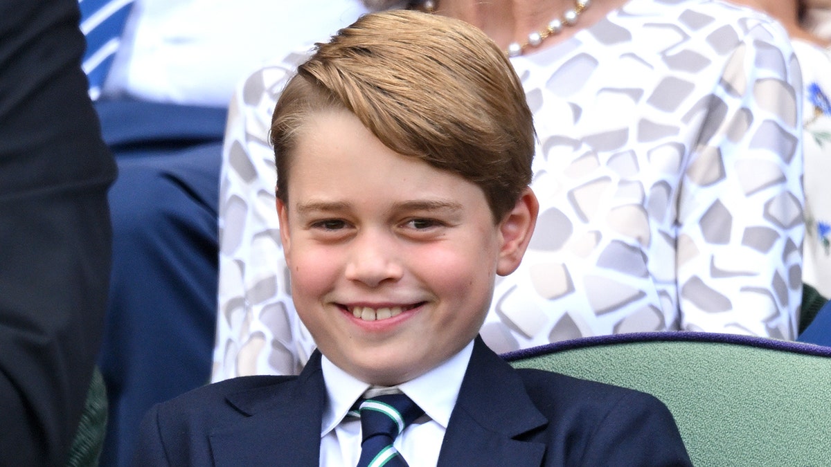 A close-up smiling photo of Prince George in a suit and tie