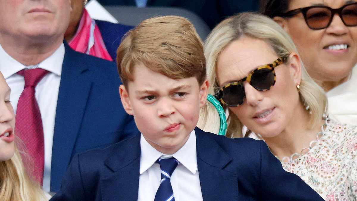 Prince George making a funny face at a polo match wearing a suit and tie