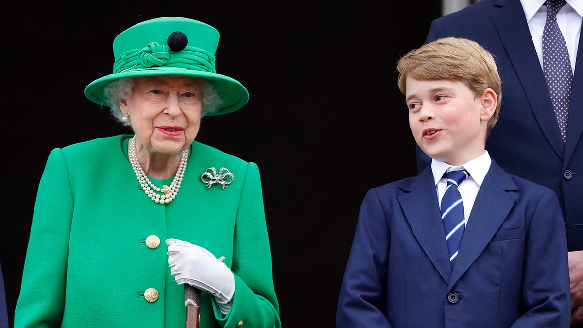 Queen Elizabeth wearing a bright green coat dress and matching hat standing next to Prince George