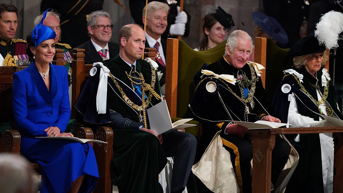 Kate Middleton in a blue dress sitting next to Prince William, King Charles and Queen Camilla