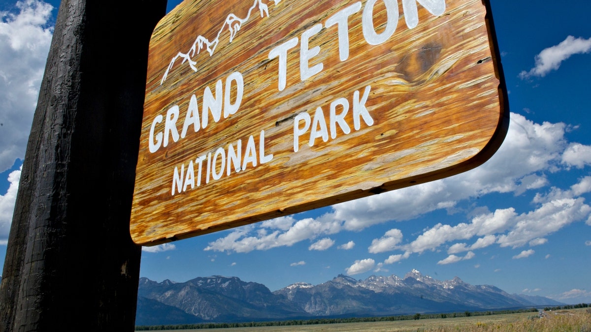 A sign for Grand Teton National Park with mountains in the background