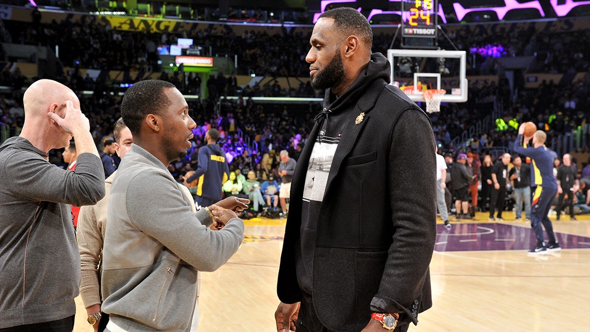 Rich Paul and LeBron James talk during a game