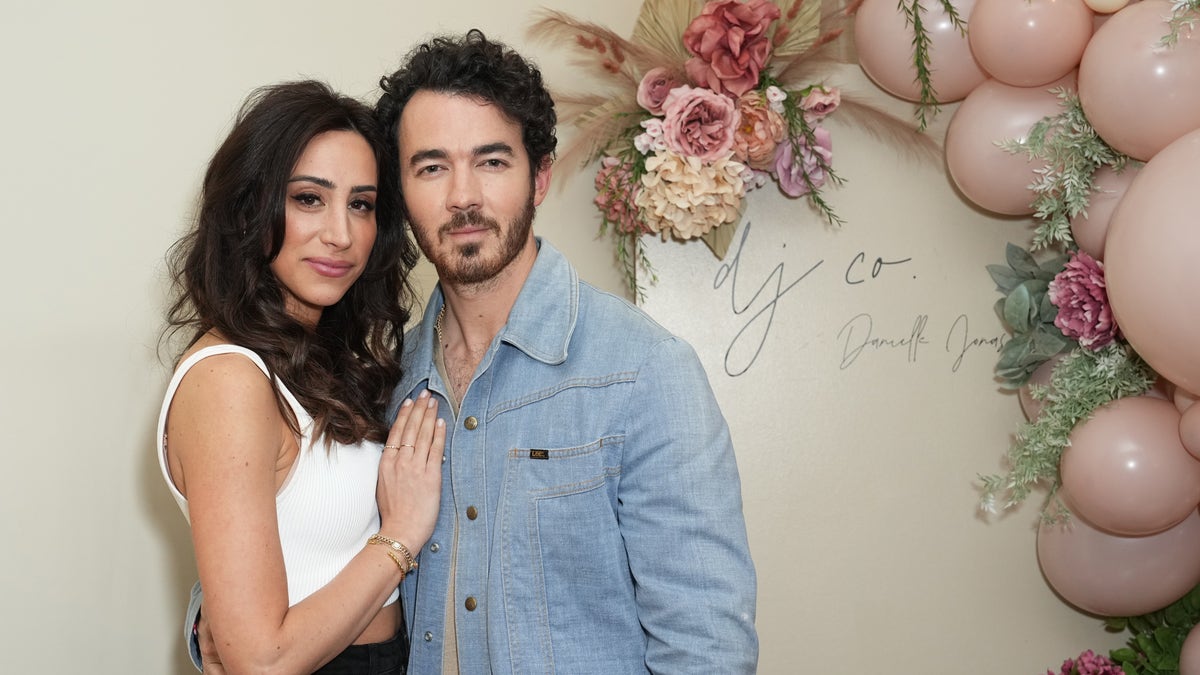 Kevin Jonas posing with wife Danielle Jonas in front of flower arch