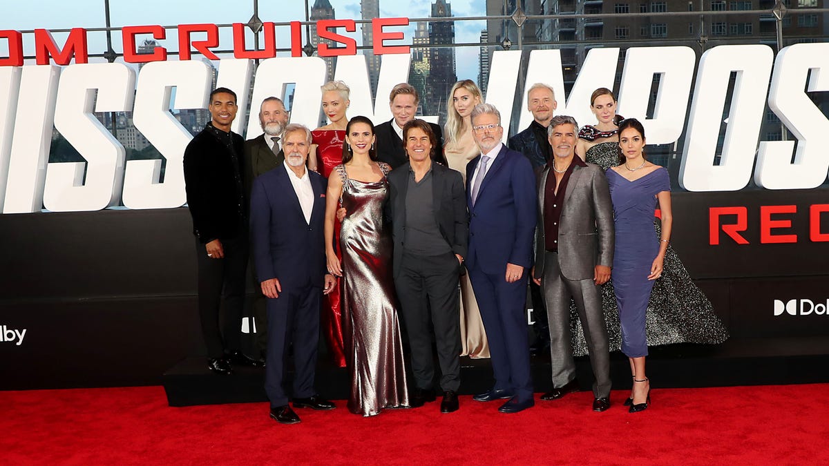 The cast of Mission: Impossible Dead Reckoning Part 1 stand together in a group, including Tom Cruise, Hayley Atwell, Simon Pegg, Rebecca Ferguson, Vanessa Kirby, and director Chris McQuarrie