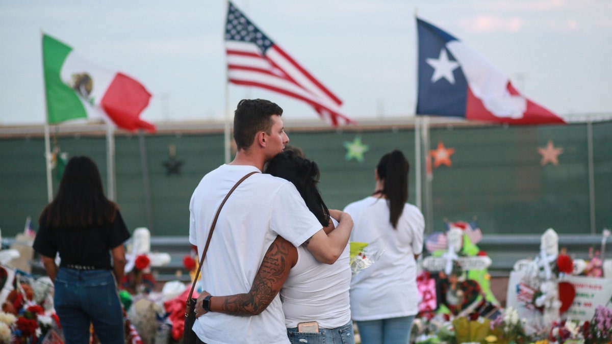 People gather at a makeshift memorial outside the El Paso, Texas, Walmart