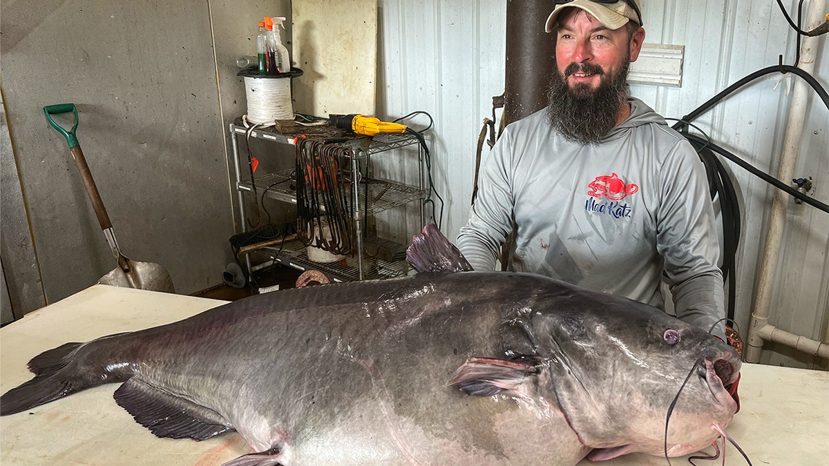 Micka Burkhart stands next to his 122-pound record catfish.