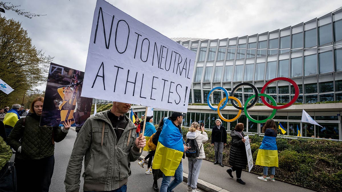 Ukrainian protesters walk past the IOC headquarters