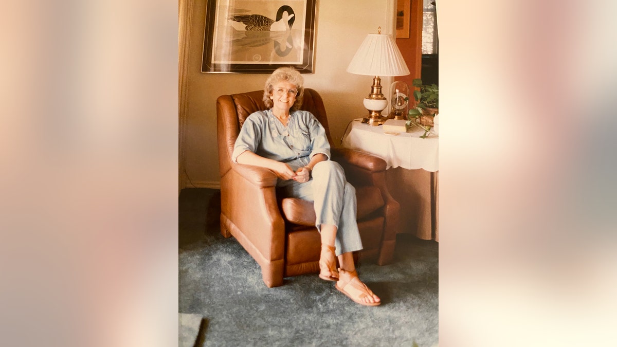 Loretta Bowersock wearing a light blue shirt and matching pants sitting on a tanned couch