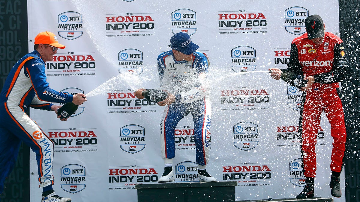 Alex Paulo, Scott Dixon, and Will Power splash champagne