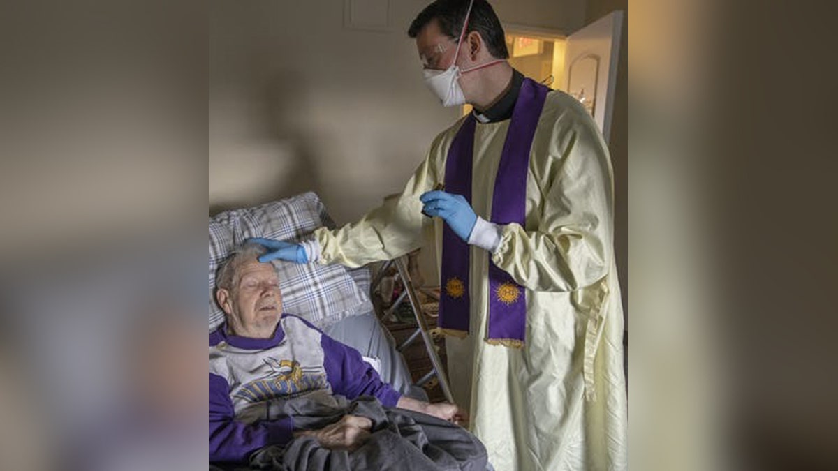 priest gives anointing of the sick to an elderly man