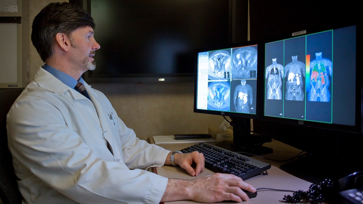 A radiologist compares a CT scan to a choline C-11 PET scan of a patient with recurrent prostate cancer