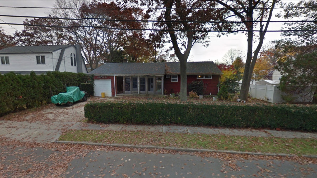 Red house with wrapped up car in driveway and leaves falling