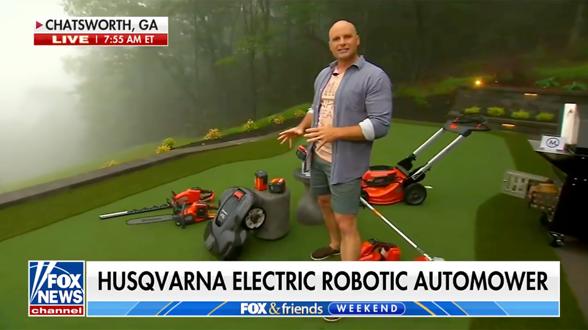 Chip Wade next to a robotic lawnmower
