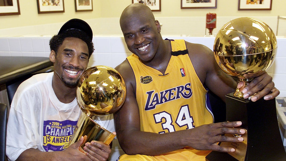 Kobe Bryant and Shaquille O'Neal hold trophies after winning a championship