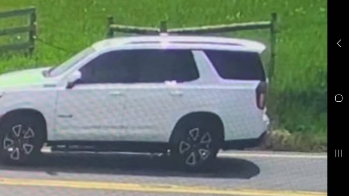 White SUV parked near wooden fence and grassy field