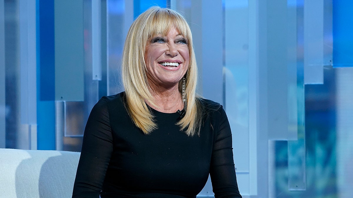 Suzanne Suzanne Somers smiles in a black top omers on TV