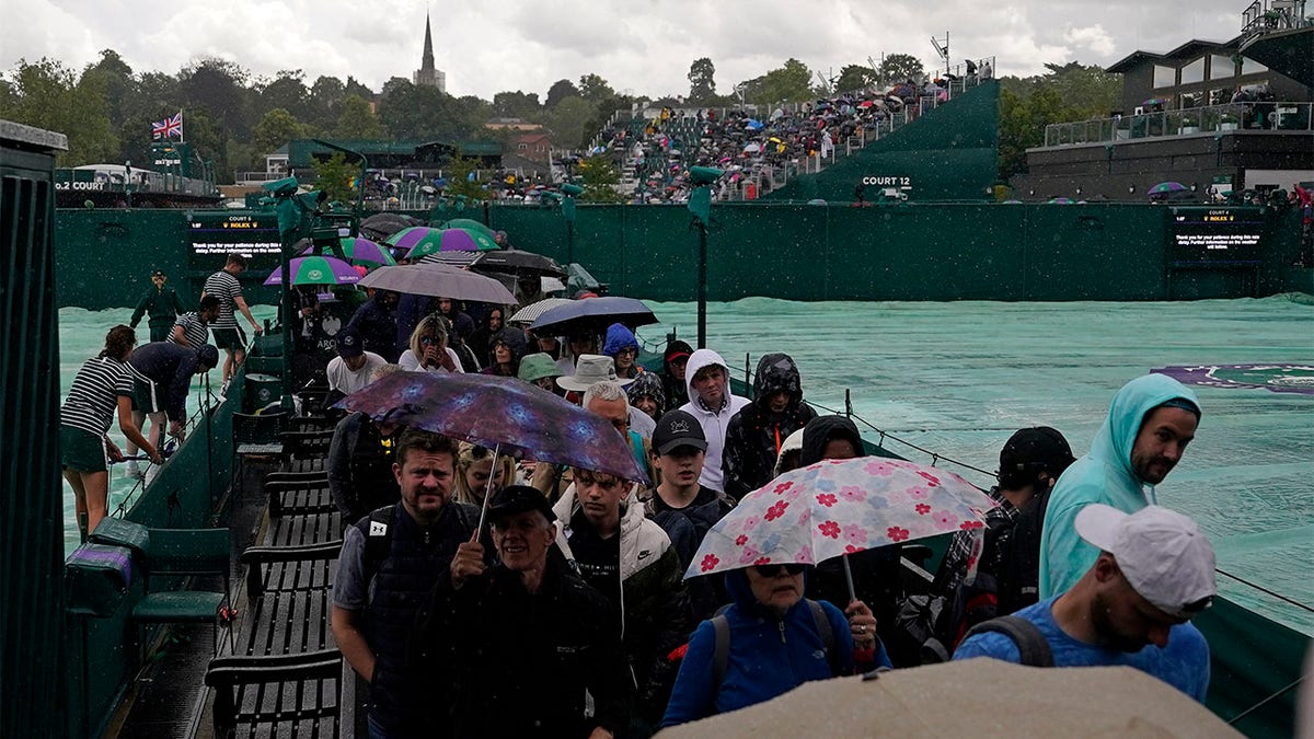 Spectators walk in rain