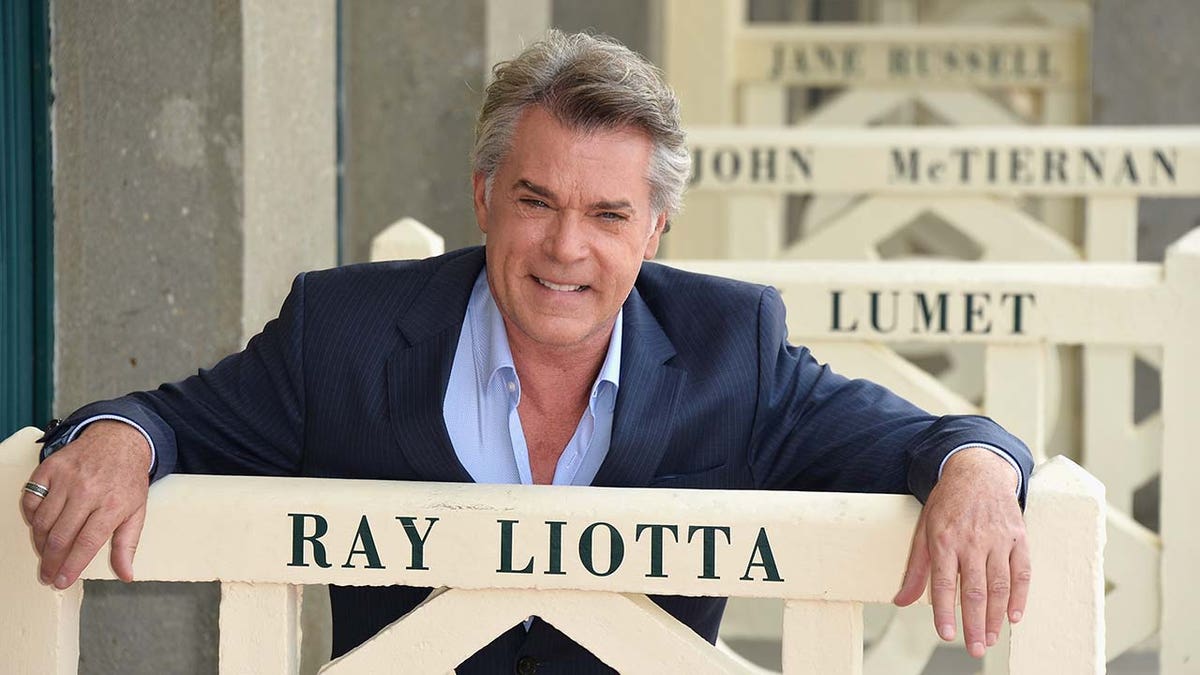 Ray Liotta posing with a sign that has his name on it