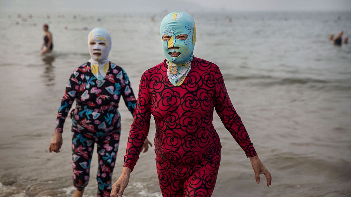 Two women wading in water wearing facekinis