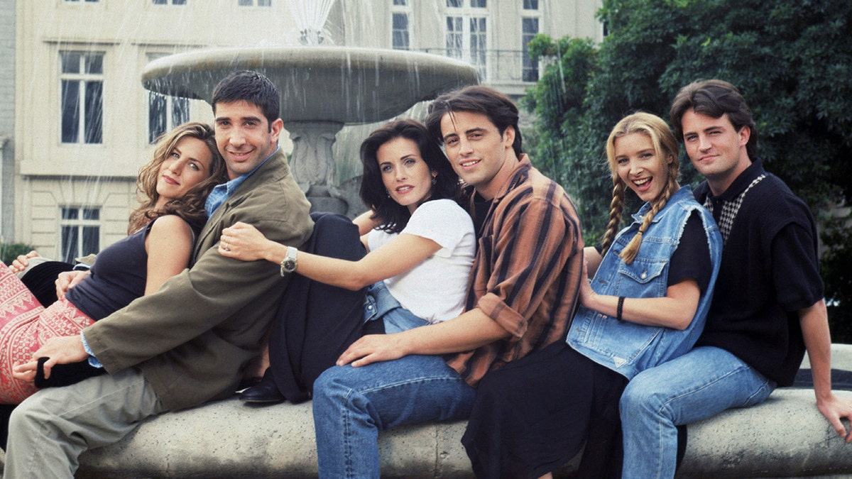 Friends cast sitting in front of the fountain featured in their opening credits