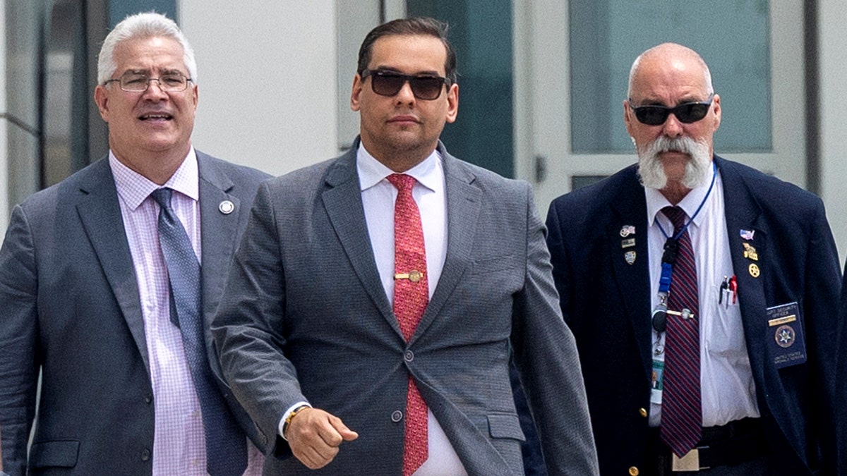 Rep. George Santos exits a Long Island court house flanked by his attorney and a staffer