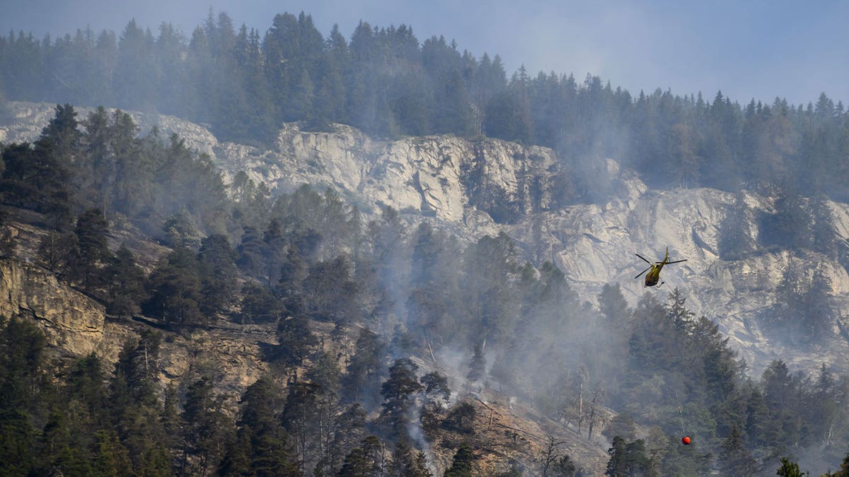 helicopter pours water on mountain fire