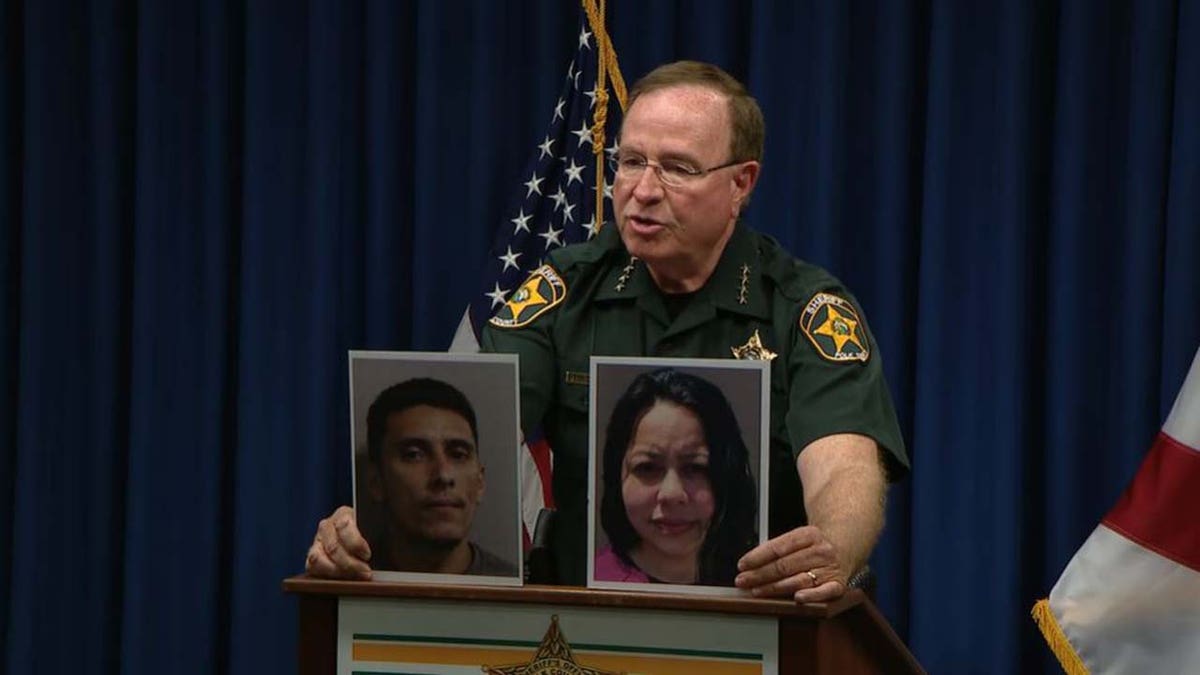 Polk County Sheriff Grady Judd holding Joel and Jazmine Rondon's mugshots