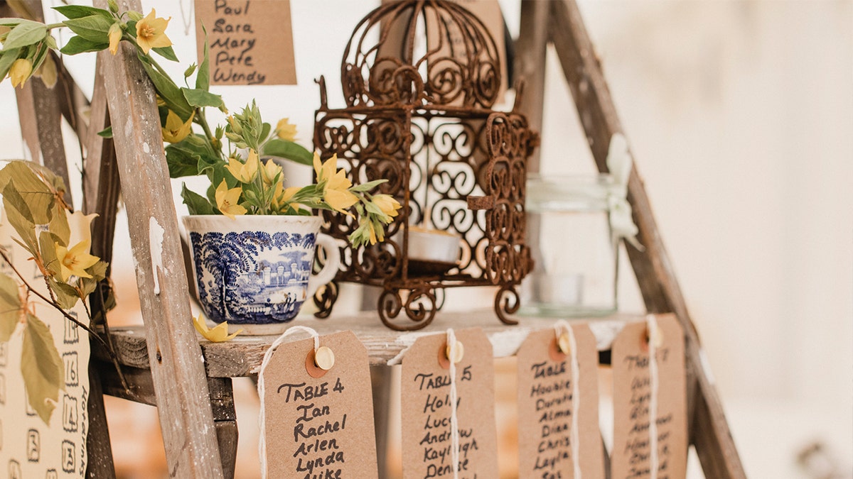 A wooden step ladder at a wedding venue with name place cards for seating arrangements.
