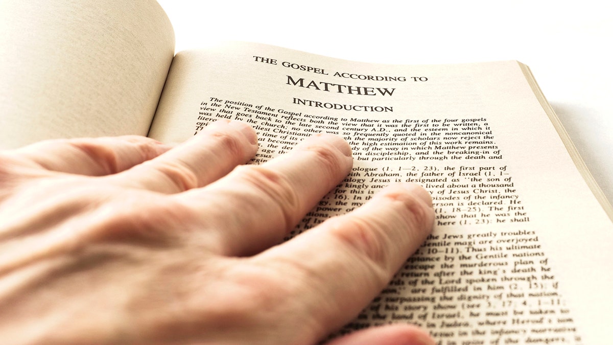 hand resting on the first chapter of the Gospel of Matthew