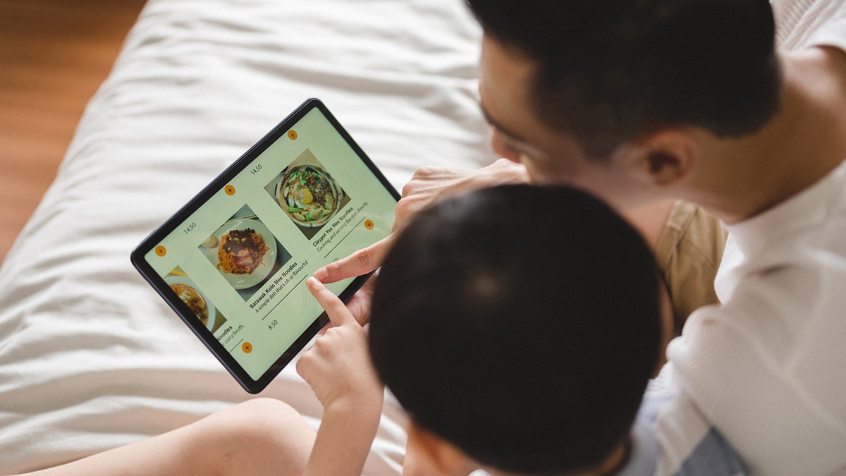 Dad and son look at food menu online.