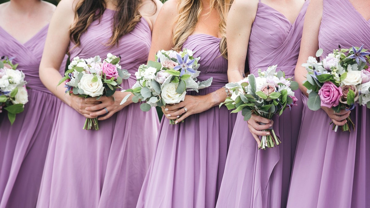 Bridesmaids in purple dresses shown without heads