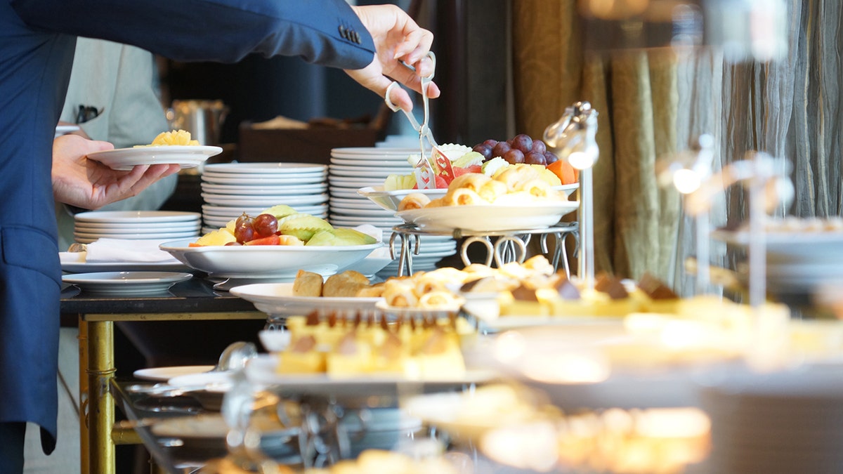 Person grabs foods at hotel buffet.