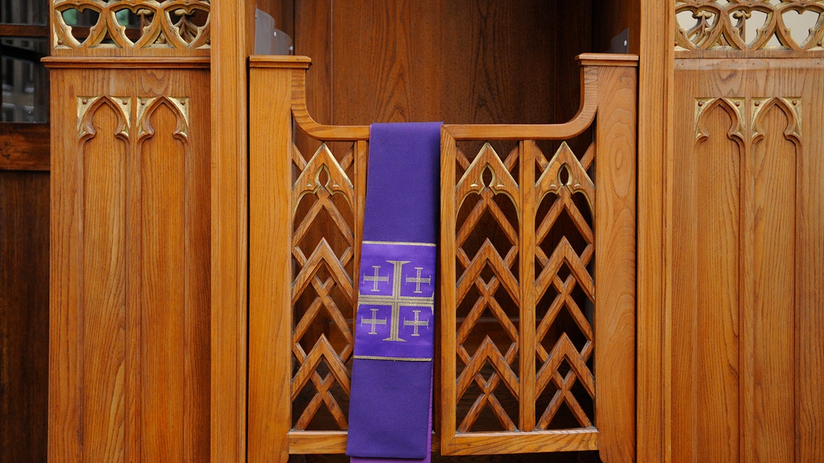a purple stole with a jerusalem cross hangs over a confessional