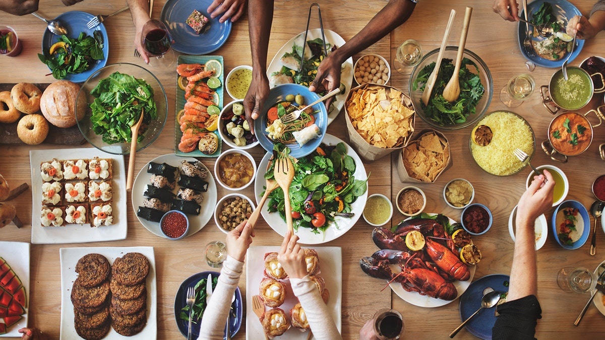 People eat at a table filled with food.