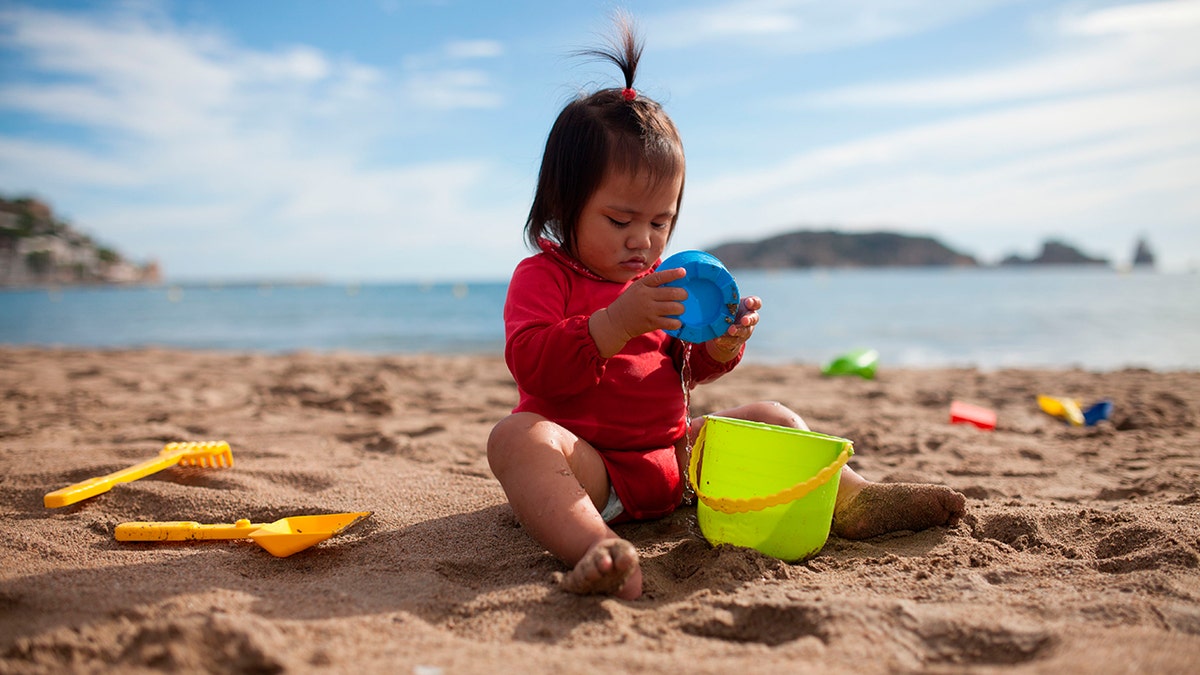 A young child playing in the sand at the beach