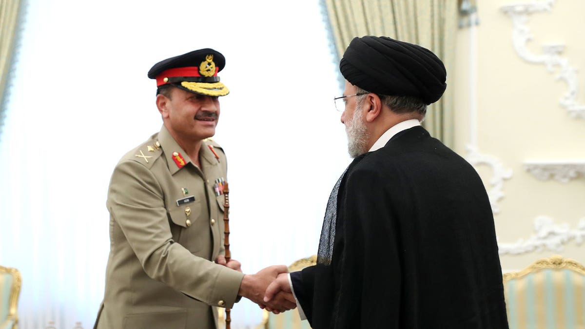 Ebrahim Raisi and Asim Munir shake hands