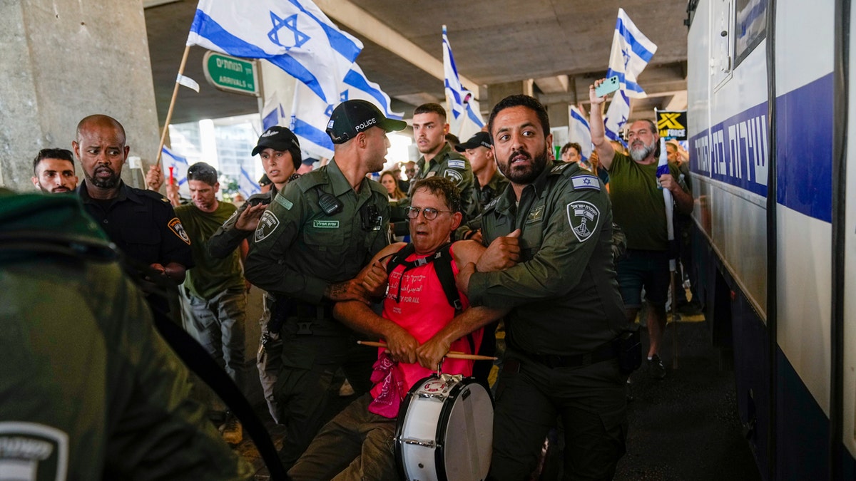 Protestor being escorted from Ben Gurion Airport in Israel