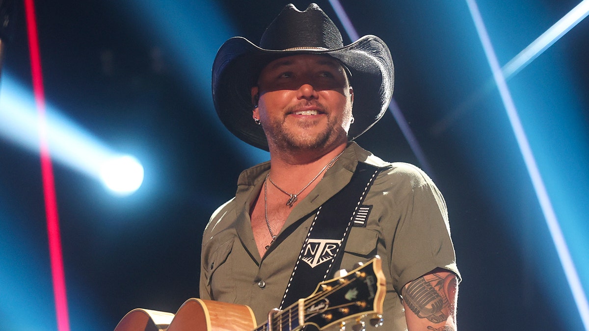 Jason Aldean wears black cowboy hat on stage while performing