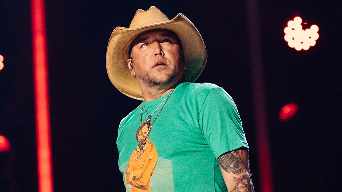 Country singer Jason Aldean performs on stage in cowboy hat and green shirt