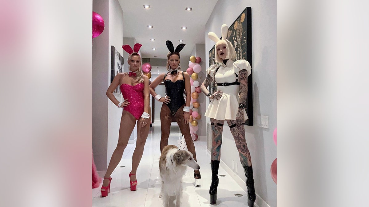 Kate Beckinsale puts her hands on hips while wearing "Playboy" bunny outfit surrounded by friends in similar attire
