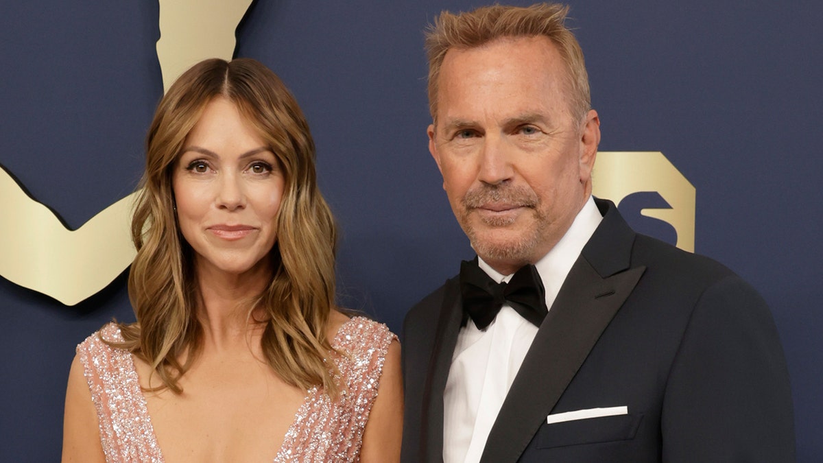 Christine Baumgartner in a sparkly plunging gown and Kevin Costner in a classic tuxedo on the carpet together