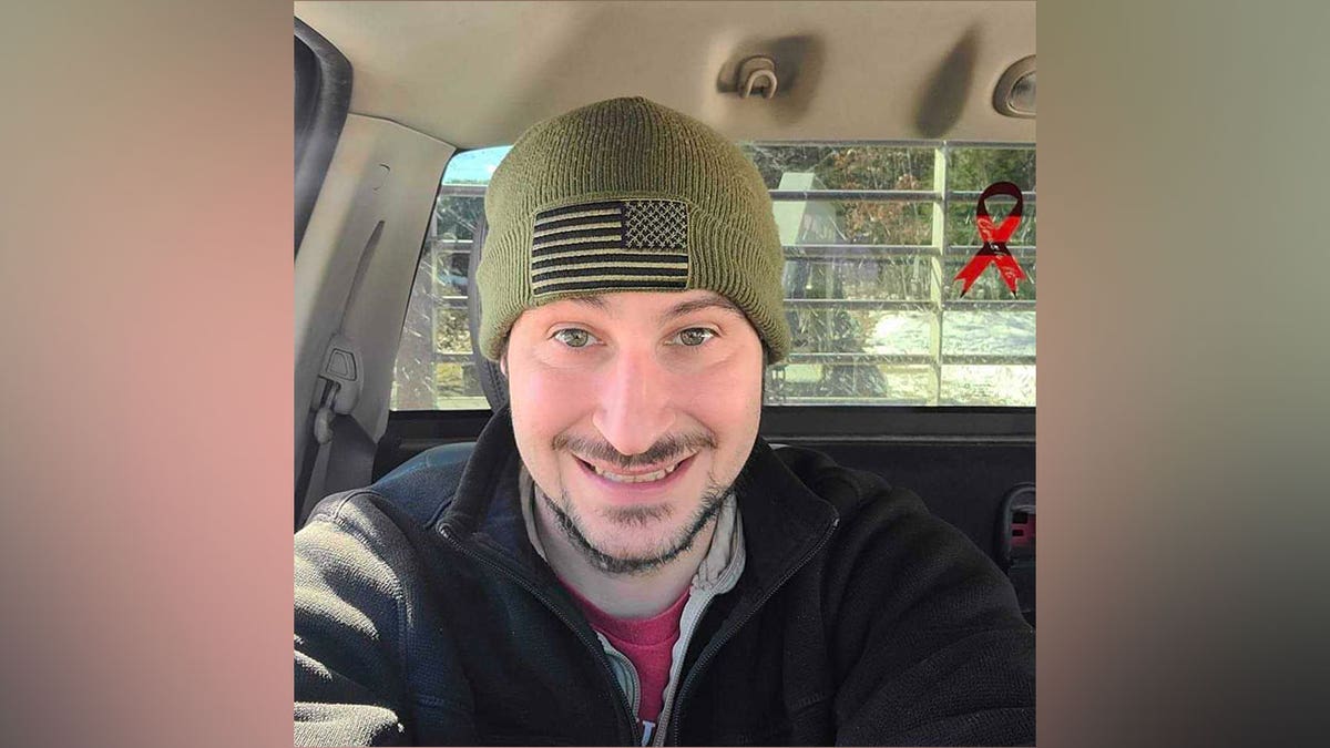 Michael Burham takes a selfie in a car while wearing a green beanie.