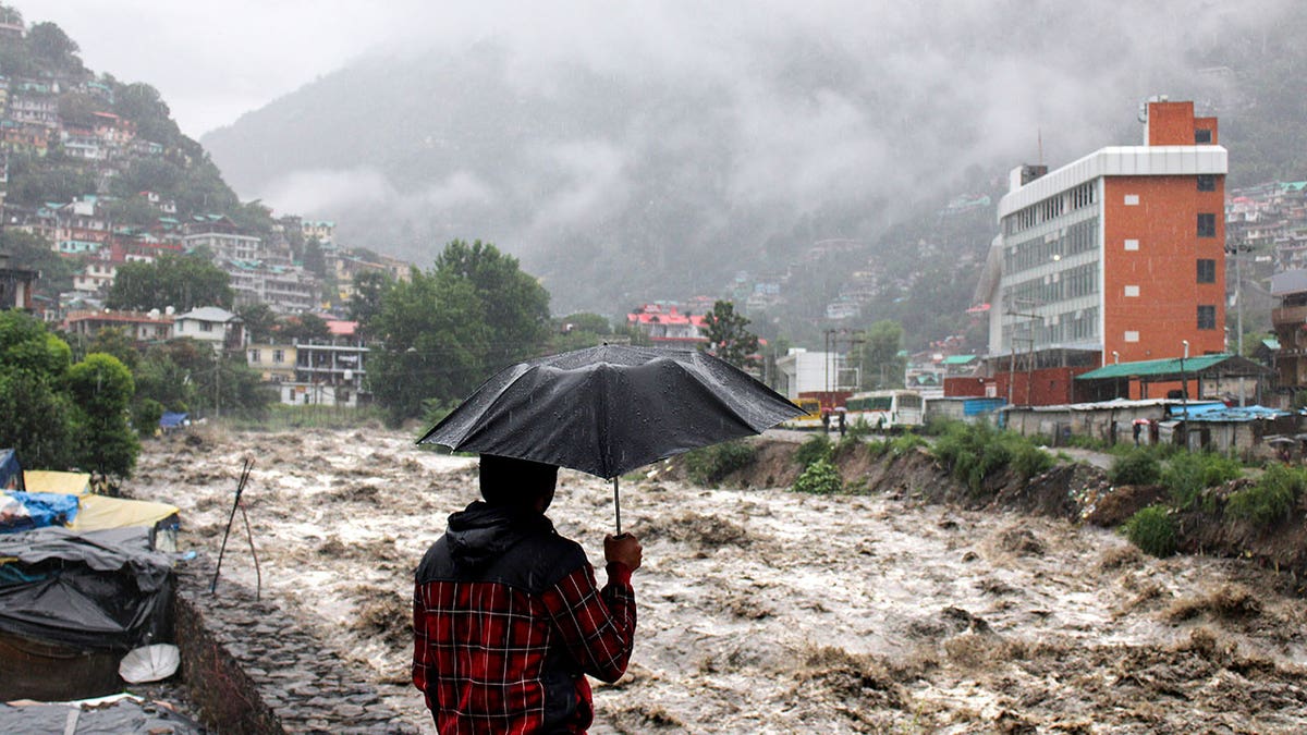 A man looks at a swollen river following heavy rains in Kullu, India, on July 9, 2023. 