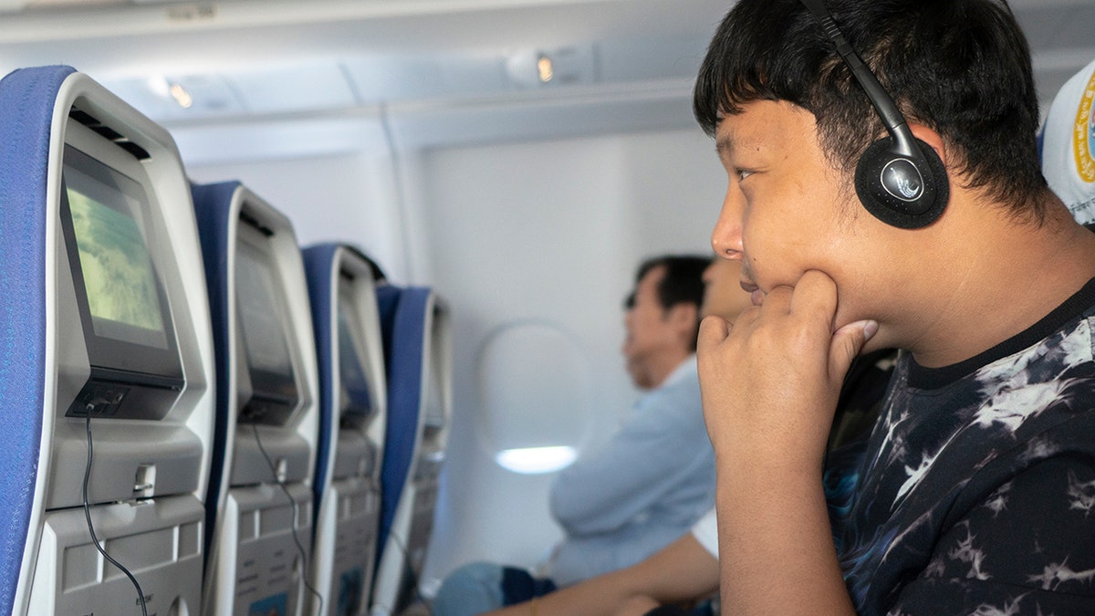 A young boy watching a movie on a plane