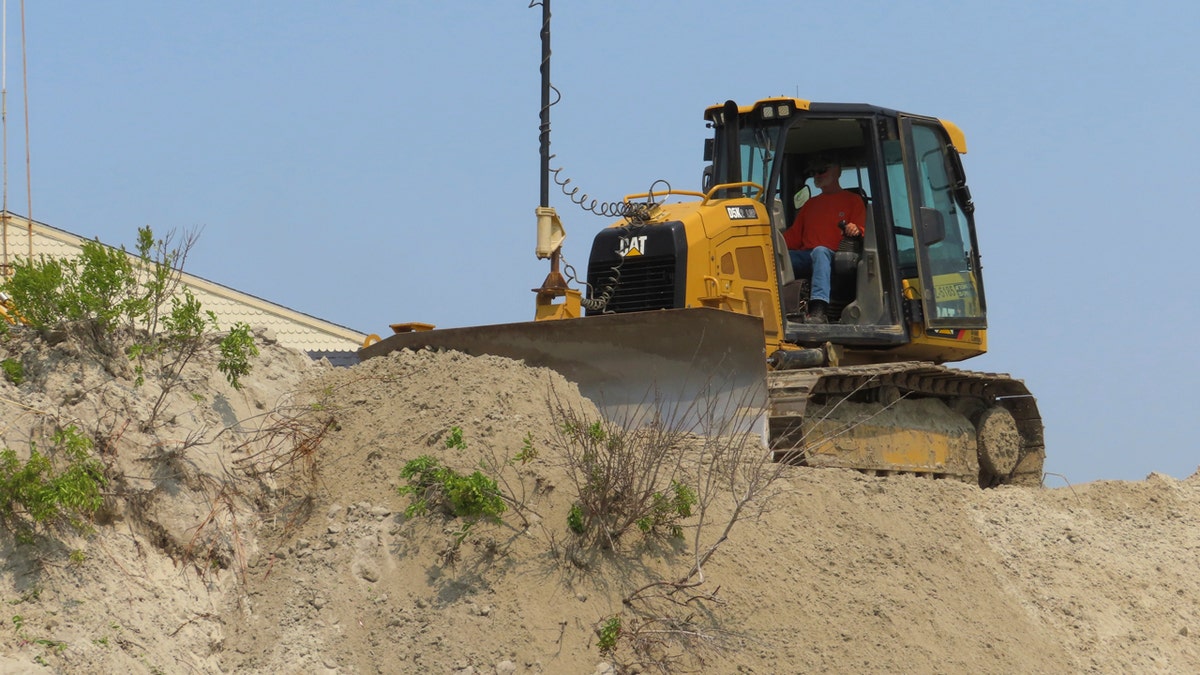Bulldozer operator repairing eroded dunes in North Wildwood, New Jersey