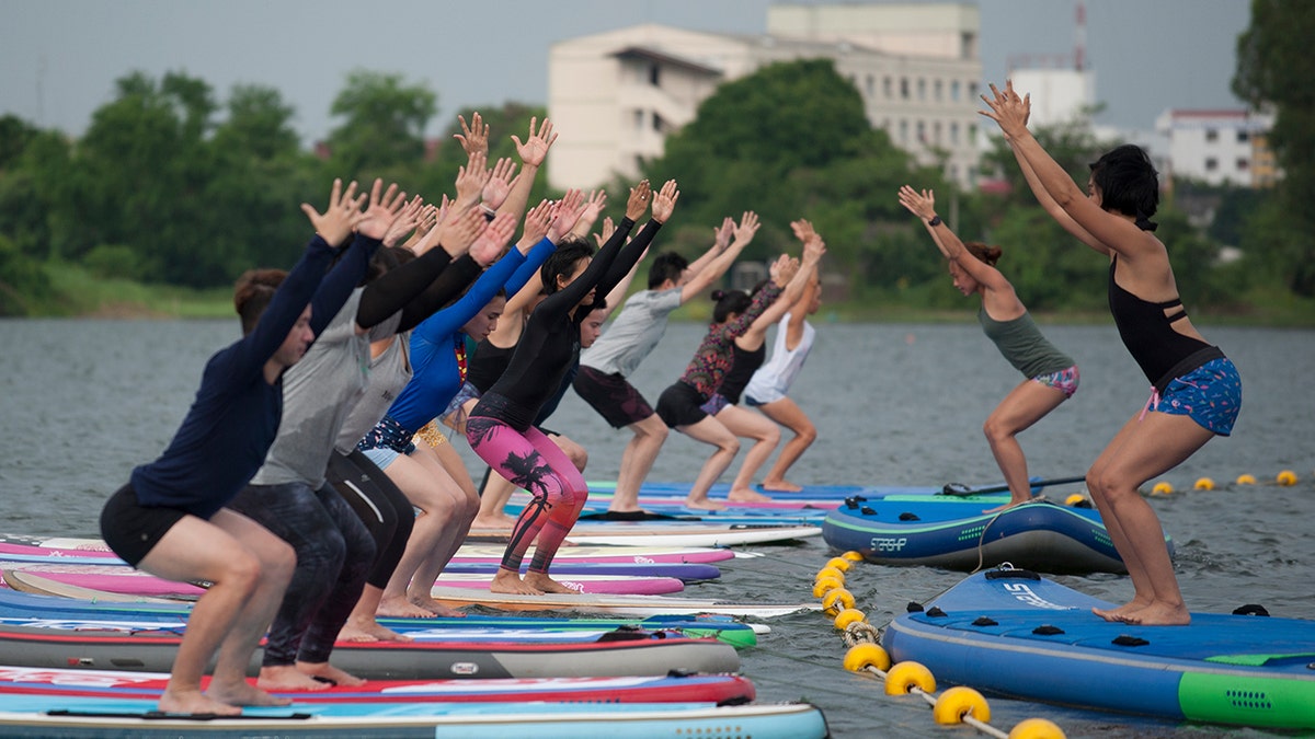 Group of people participating in paddleboard yoga
