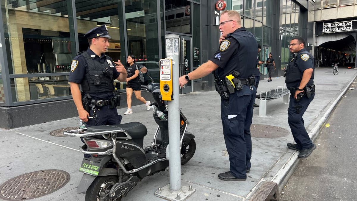 NYPD officers standing near scooter