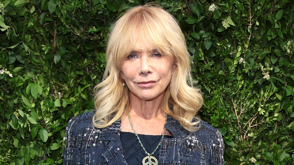 Rosanna Arquette walks red carpet wearing sparkling jacket and necklace