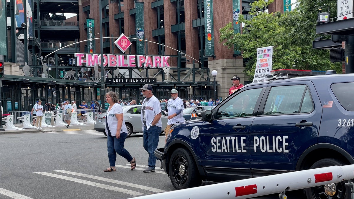 Baseball fans cross in front of Seattle police car