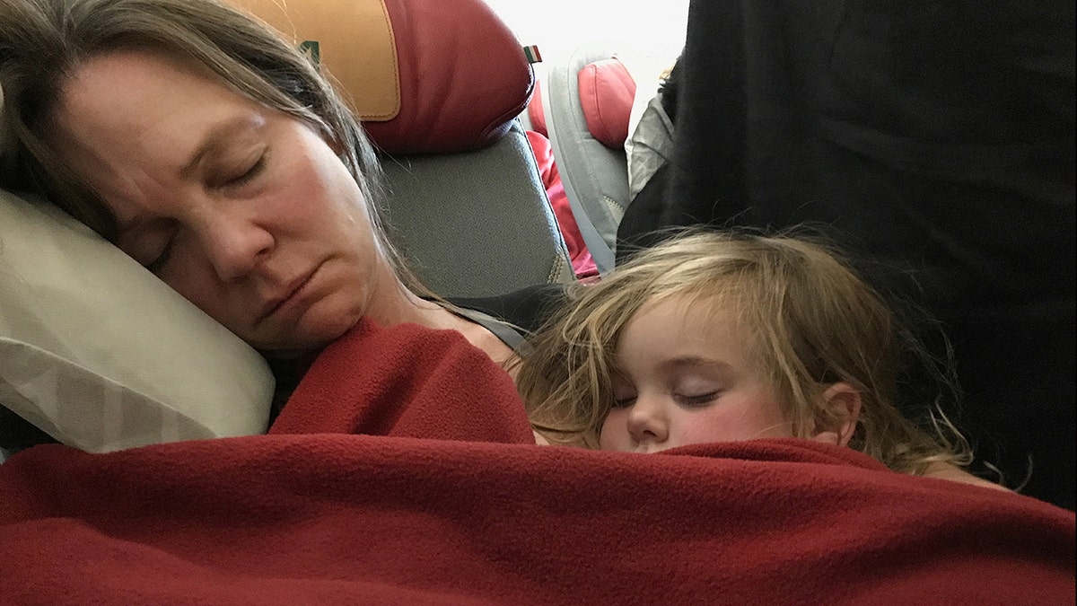 A mother and daughter asleep on a plane